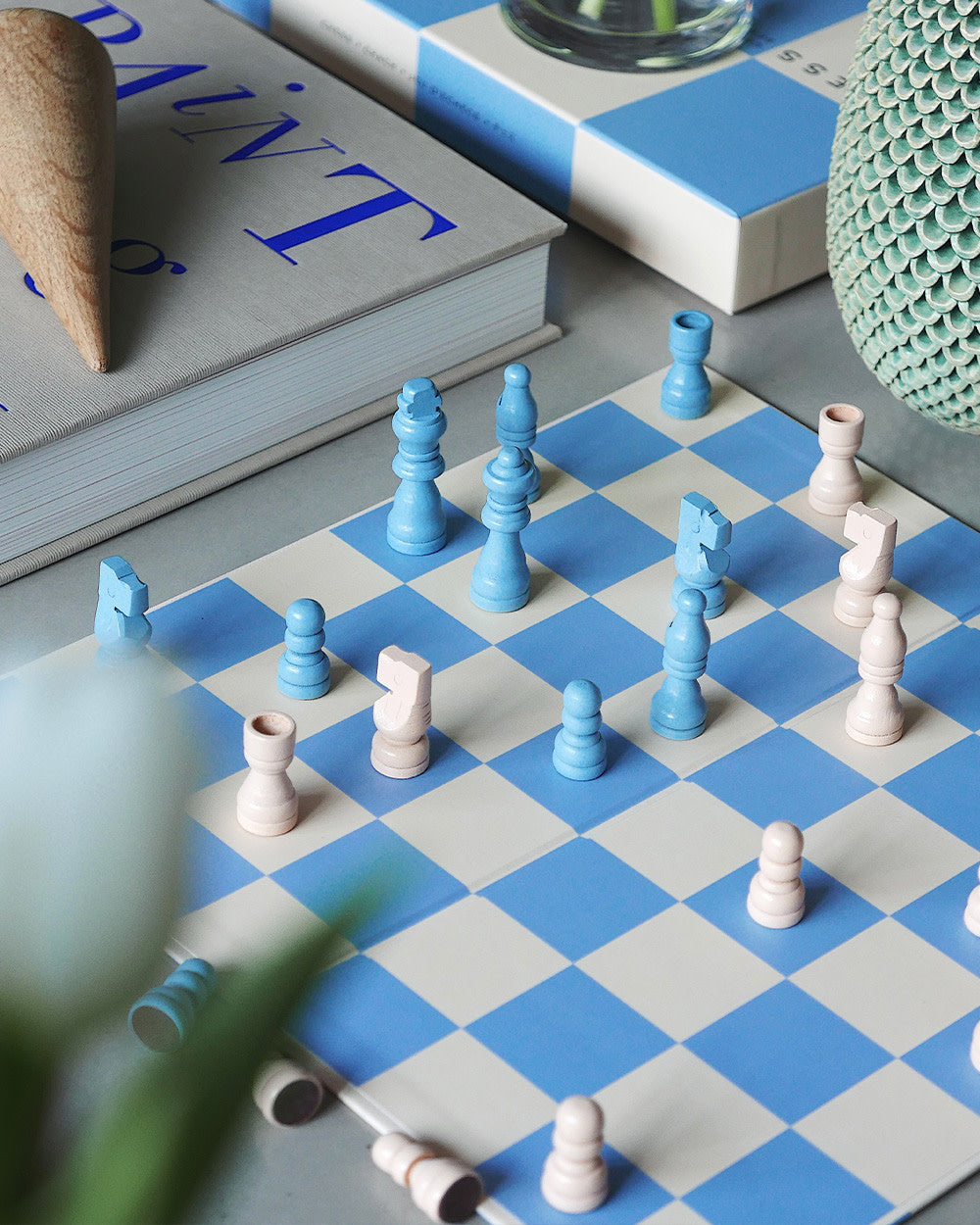Chess pieces in play on blue and beige checkered board