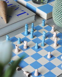 Chess pieces in play on blue and beige checkered board