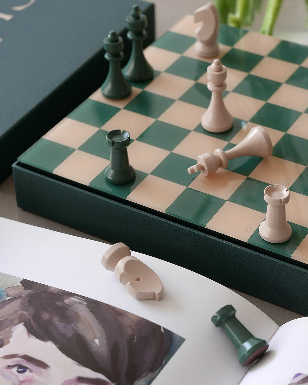 Green and cream chess board in play beside books