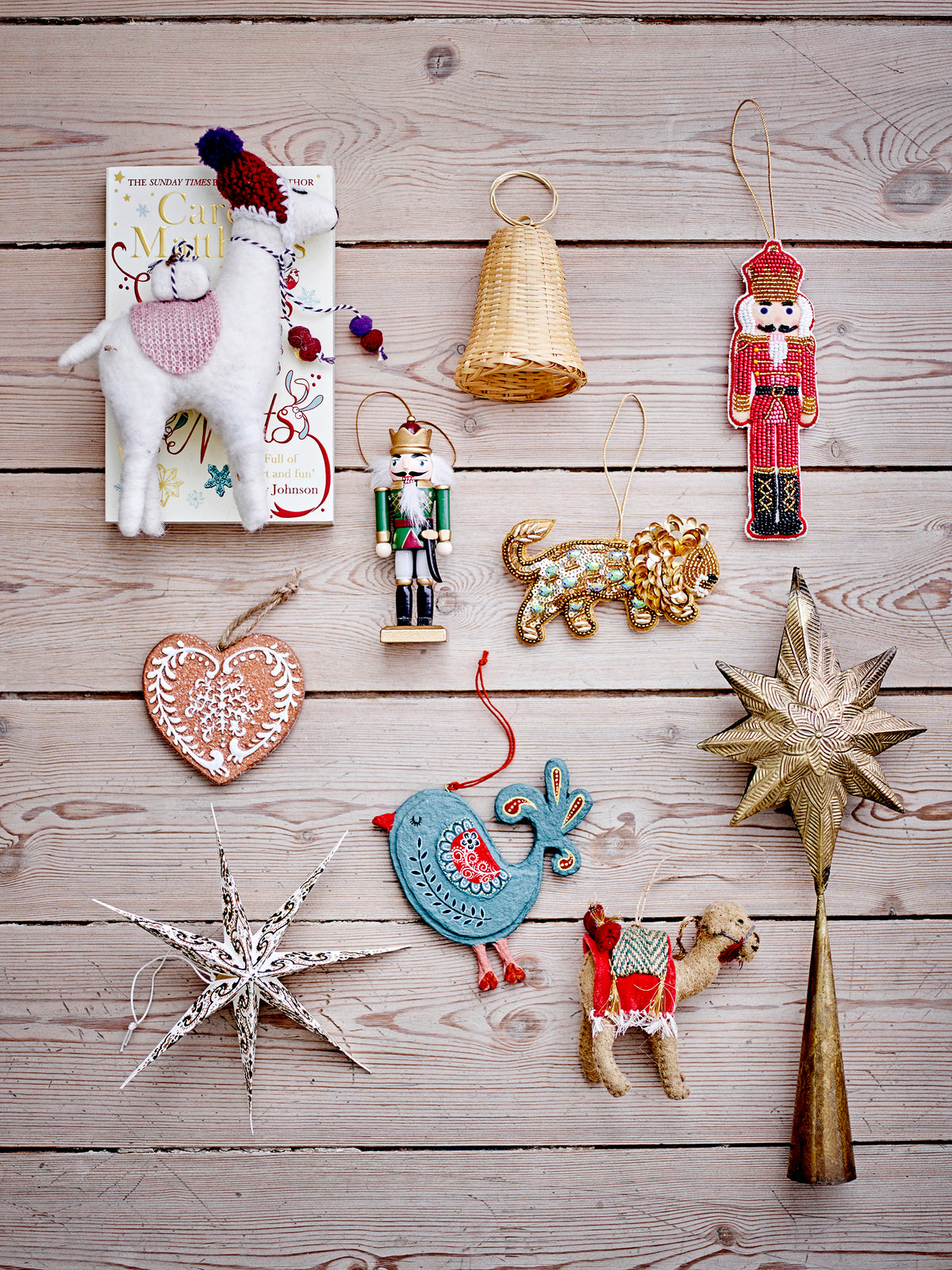 Flat lay of assorted Christmas ornaments including nutcrackers, stars, and animal figures on wooden background