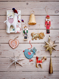 Flat lay of assorted Christmas ornaments including nutcrackers, stars, and animal figures on wooden background