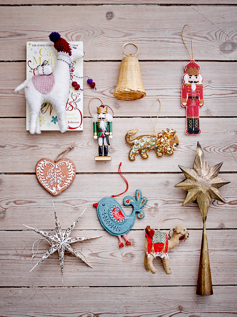 Flat lay of assorted Christmas ornaments including nutcrackers, stars, and animal figures on wooden background
