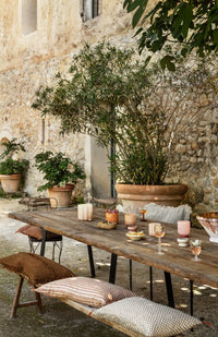 Clara votives by Olsson & Jensen on a long outdoor dining table in a sunny courtyard