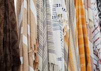 Close-up of hanging throws including warm honey and ecru striped recycled cotton design