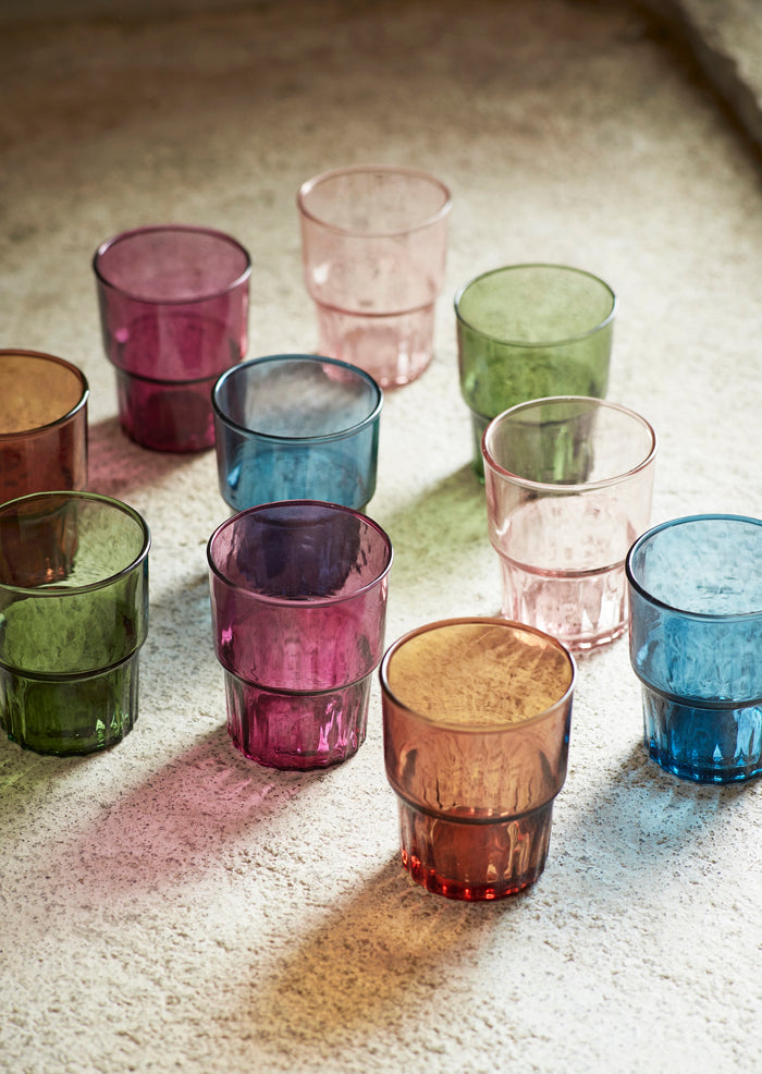 collection of colourful drinking glasses in natural light on stone surface
