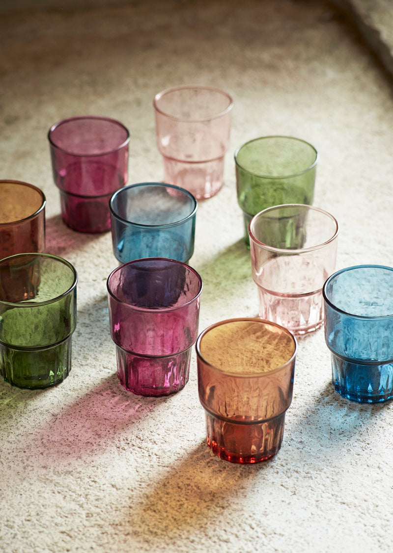 collection of colourful drinking glasses in natural light on stone surface

