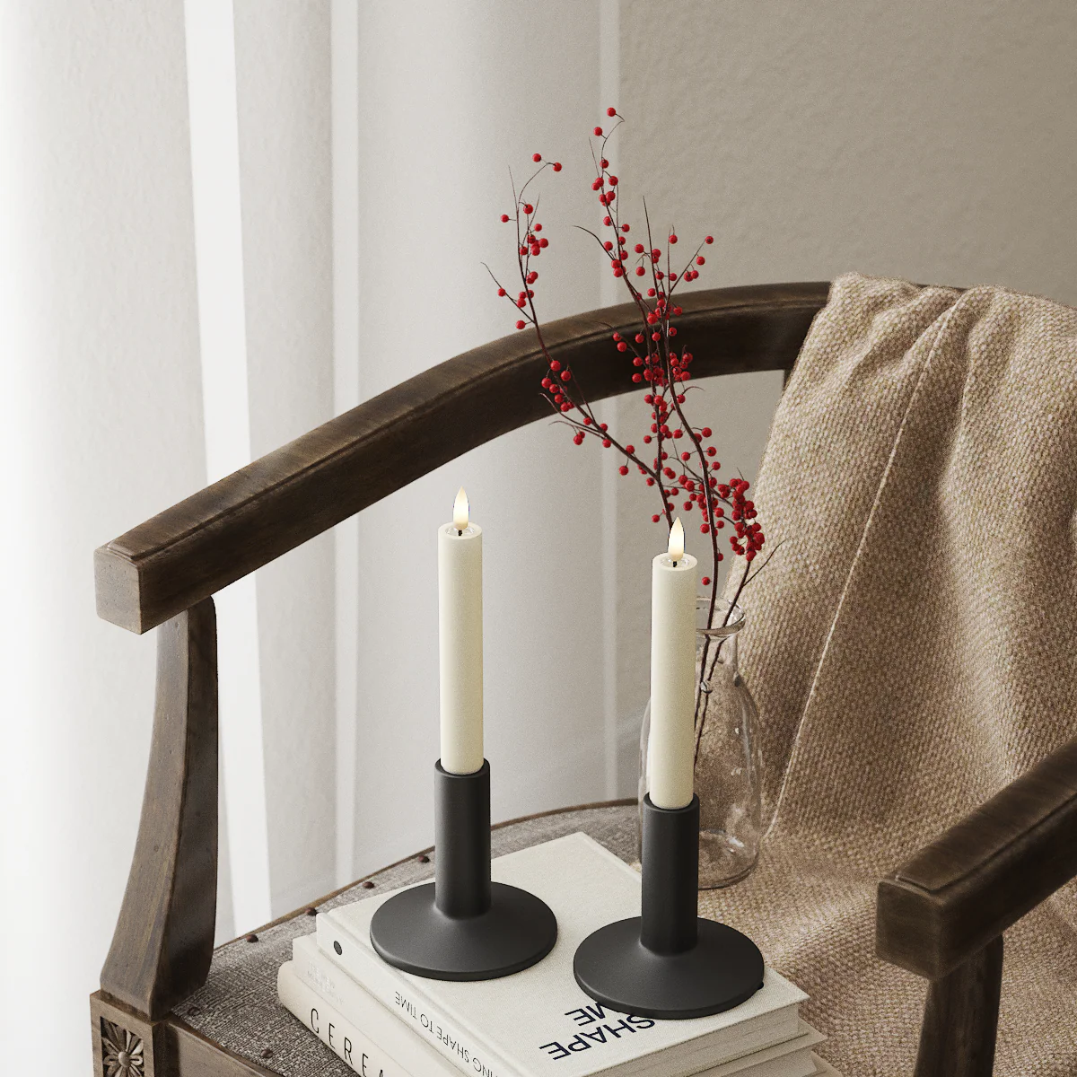 Alt text: Cream LED dinner candles on a chair with soft textiles and red berry stems, giving a cosy Nordic feel.
