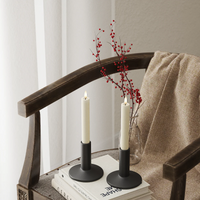 Alt text: Cream LED dinner candles on a chair with soft textiles and red berry stems, giving a cosy Nordic feel.
