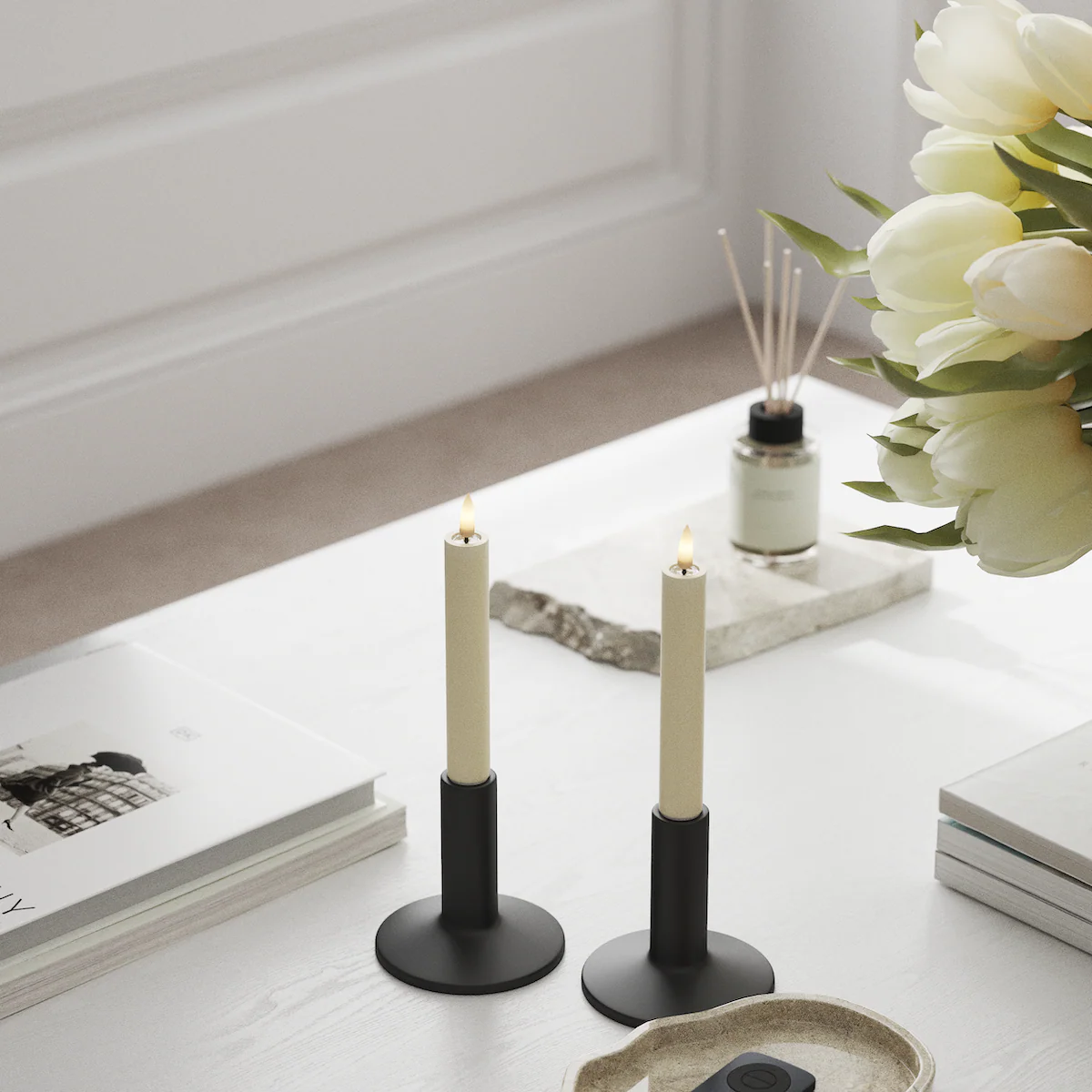 Cream LED dinner candles on a bright white table with tulips and a diffuser, creating a calm and minimal everyday setting.
