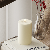 cream LED candle casting a warm glow in a winter-inspired interior scene
