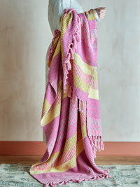 person holding pink and yellow Isnel striped throw showing soft woven texture