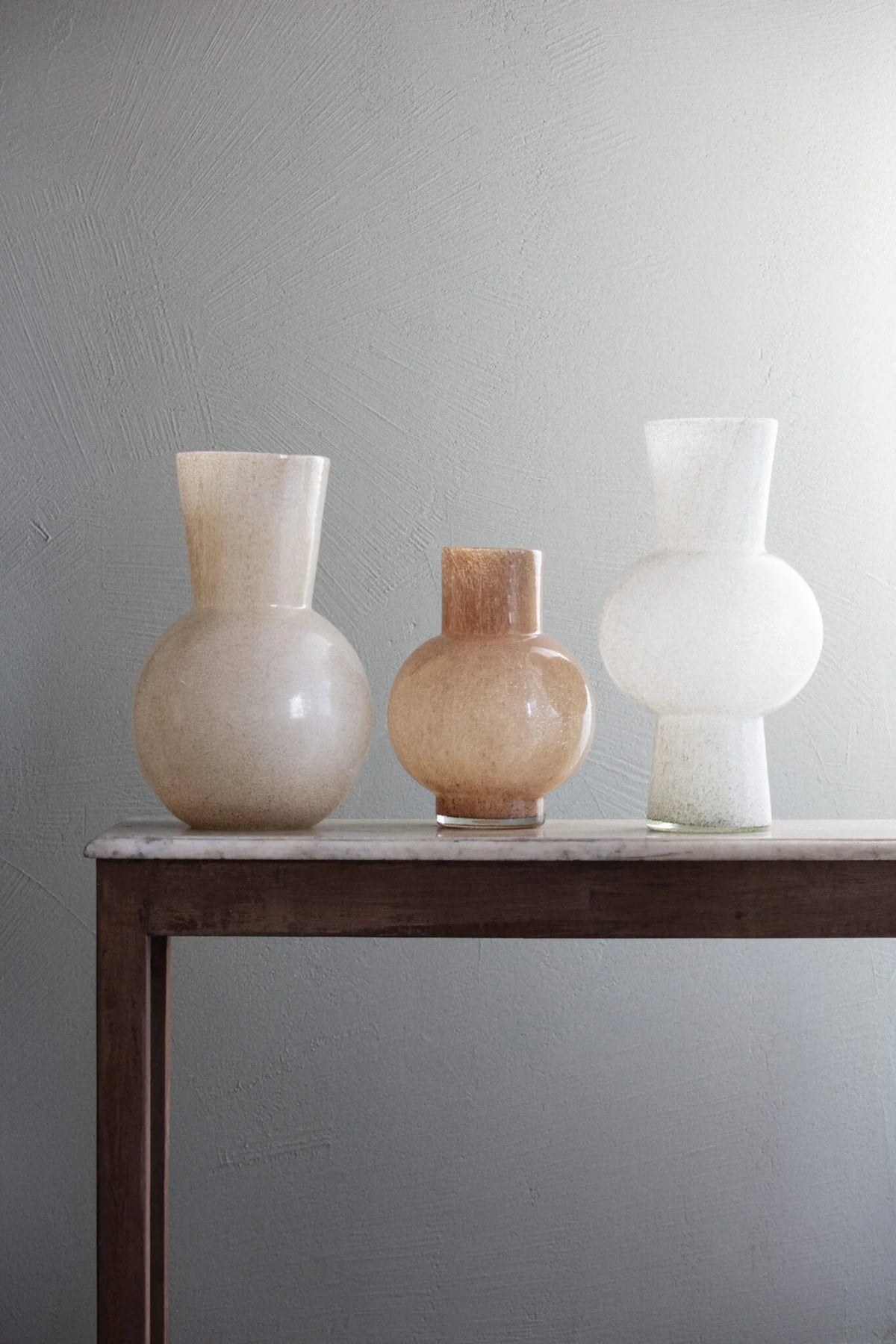 Dune sand glass vase by Olsson & Jensen styled with two other glass vases on a dark wooden console