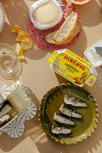 Eden olive green plate by Olsson & Jensen on a table with sardines, bread and snacks