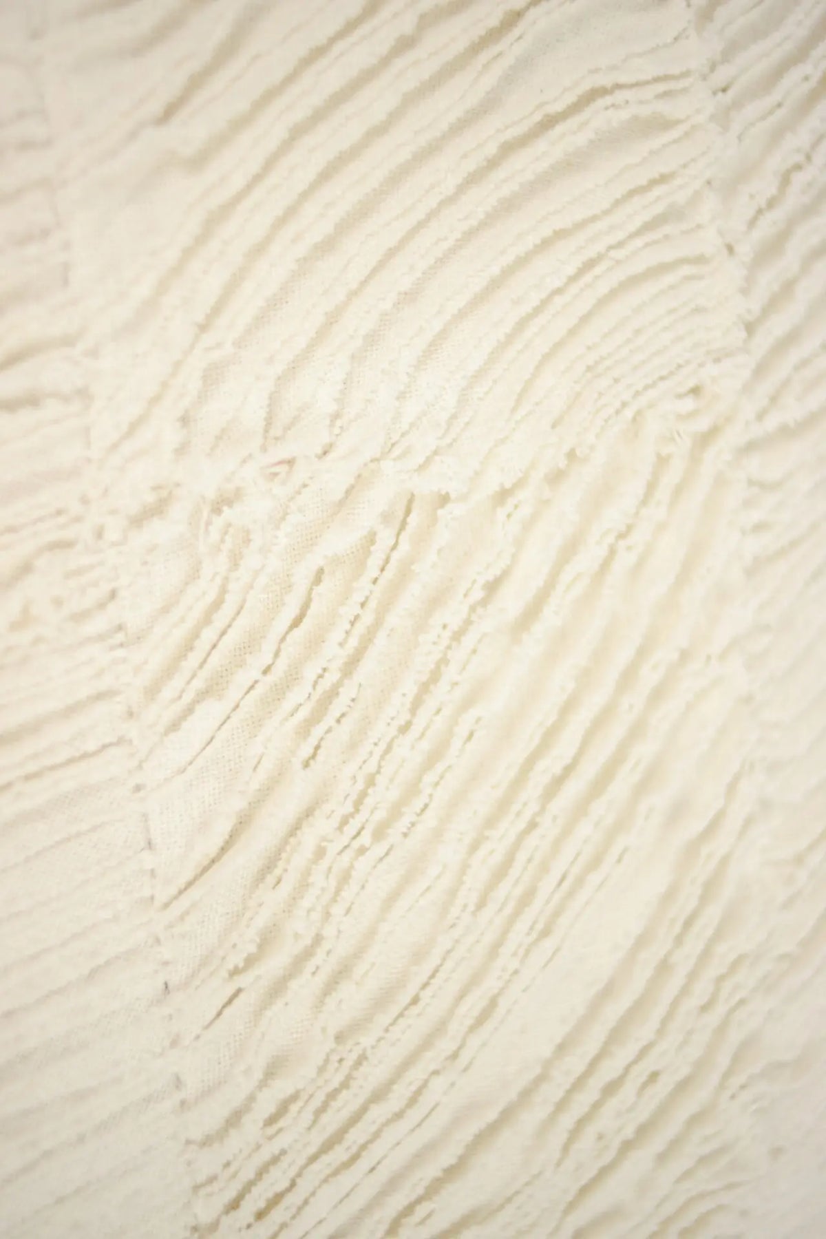 Close-up of the wave-like raw-edged cotton texture on the Elba cushion by Olsson & Jensen