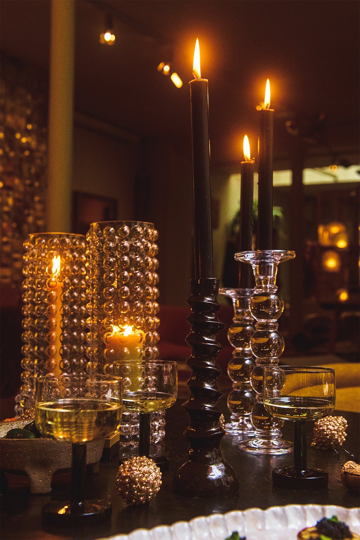 Emina candle holders by Olsson & Jensen with lit taper candles and glassware