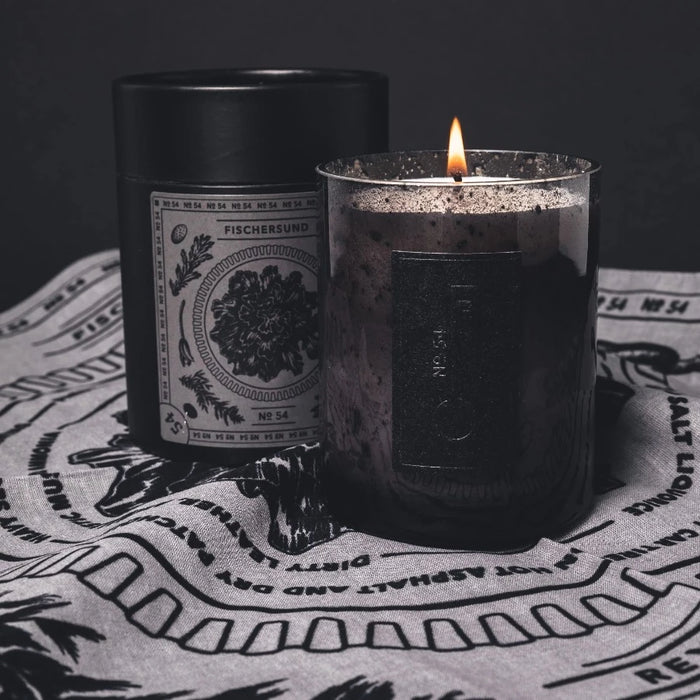 fischersunds no. 54 scented candle burning in its dark grey glass jar and stood on its bandana