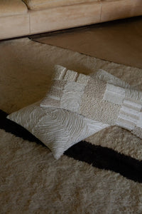Franca patchwork cushion by Olsson & Jensen styled with other textured cushions on a wool rug
