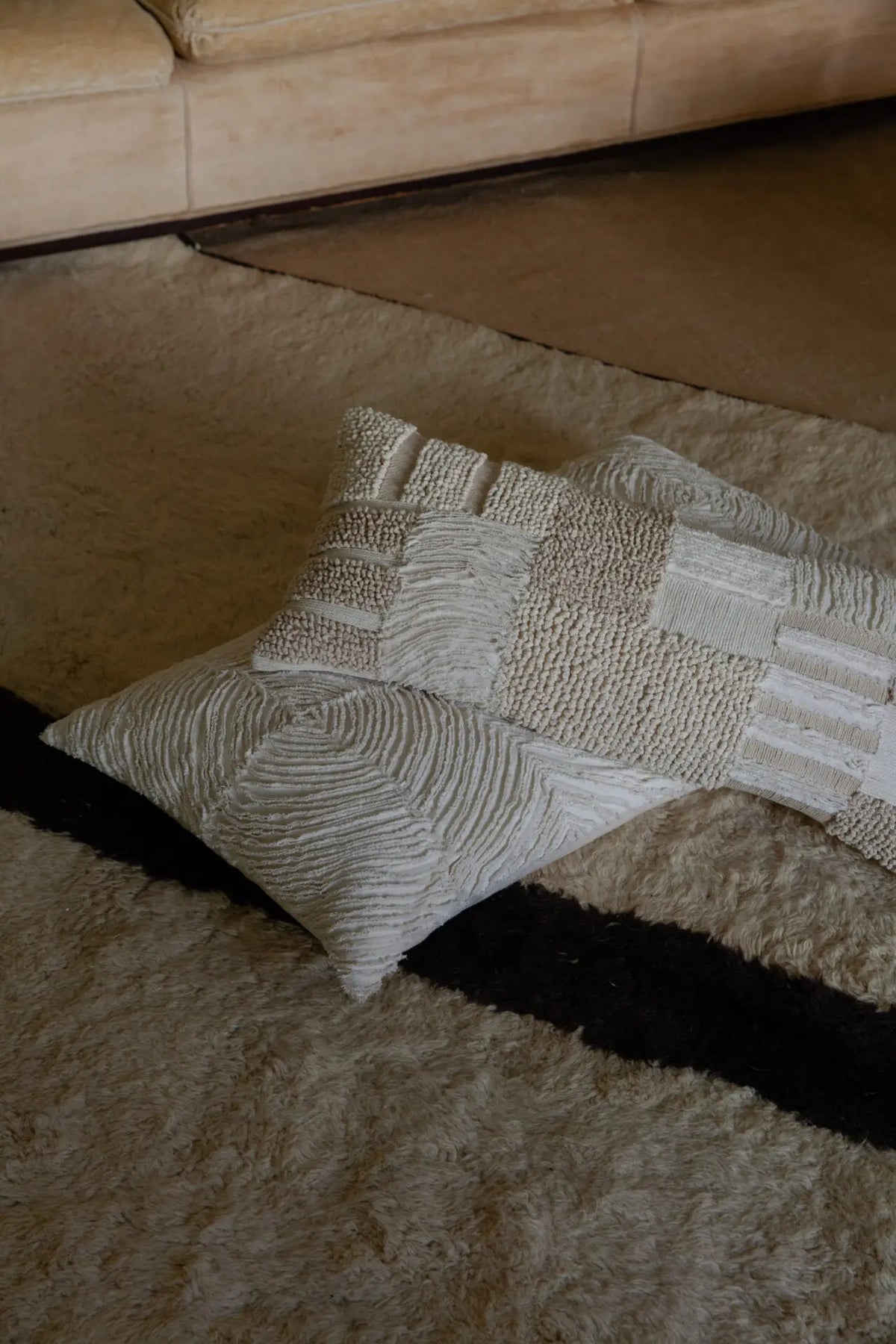 Franca patchwork cushion by Olsson & Jensen styled with other textured cushions on a wool rug