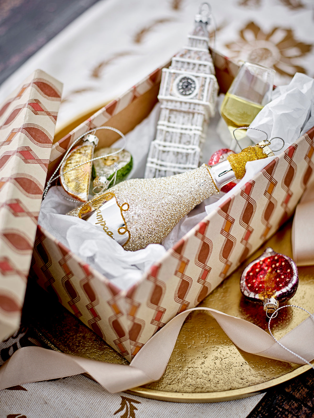 Gift box with glass Christmas ornaments including Big Ben, champagne bottle, and fruit baubles