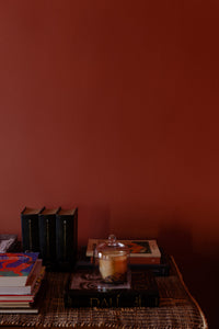 Glass dome by Olsson & Jensen over a candle on a sideboard against a red wall