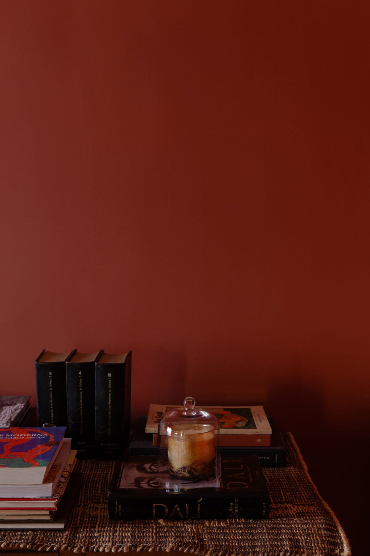 Glass dome by Olsson & Jensen over a candle on a sideboard against a red wall