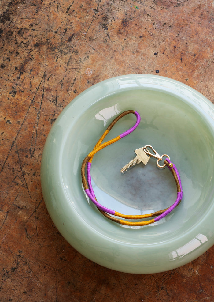 green glass bowl styled with colourful key lanyard on rustic table
