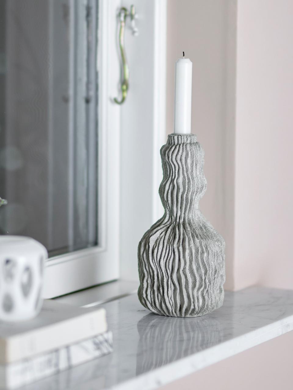 Tall polyresin candle holder with wavy surface texture on marble windowsill