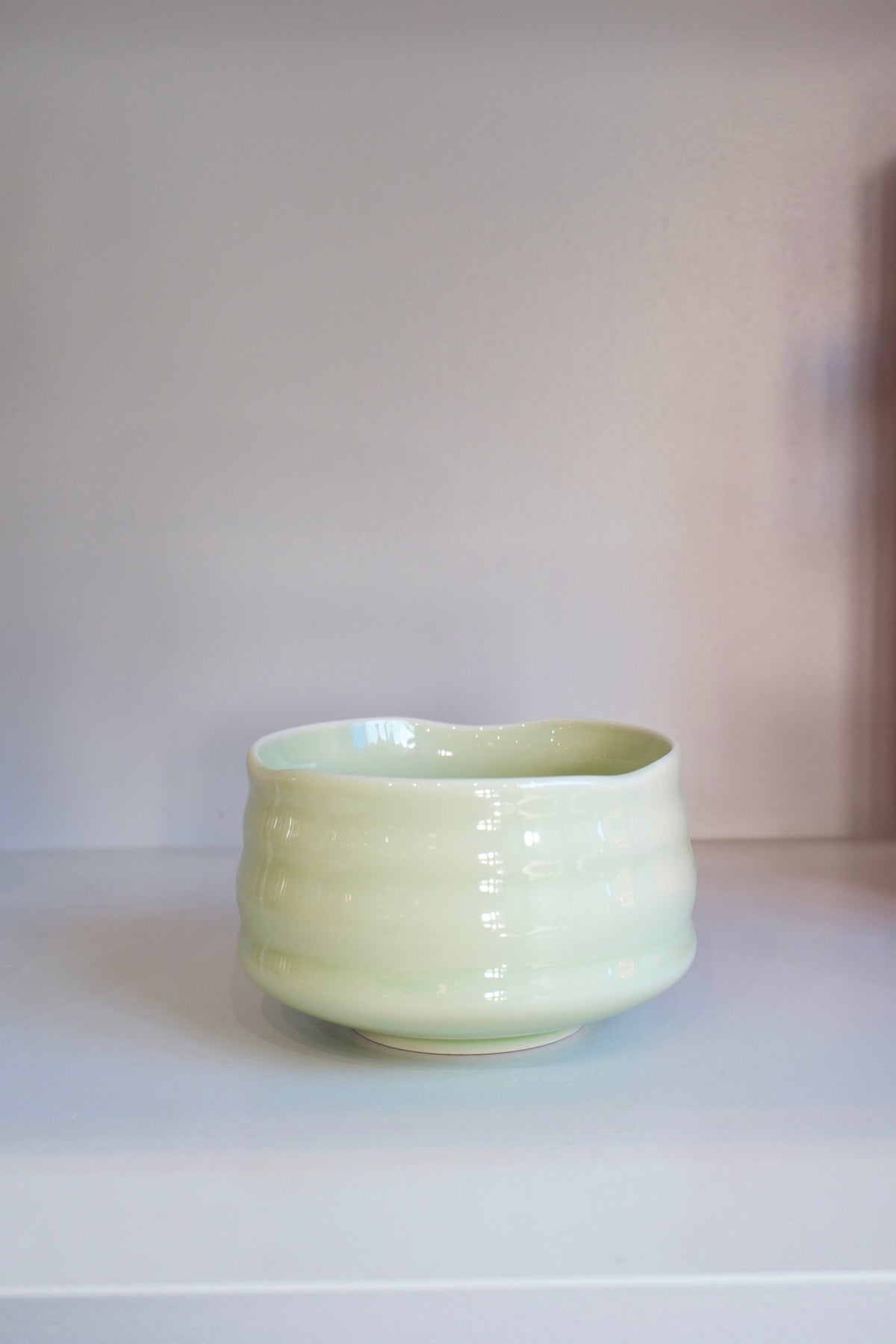 handmade pastel green matcha bowl with glossy ceramic glaze on a shelf