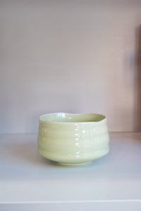 handmade pastel green matcha bowl with glossy ceramic glaze on a shelf