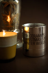 HKLIVING 70s Ceramics Winter Woods candle glowing beside silver packaging – Christmas edition

