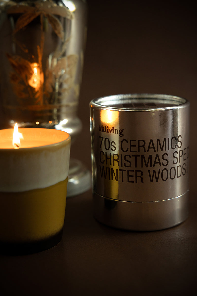 HKLIVING 70s Ceramics Winter Woods candle glowing beside silver packaging – Christmas edition
