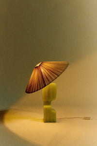 ivory pleated lampshade by HKLIVING lit on a sculptural green lamp base for warm ambient lighting