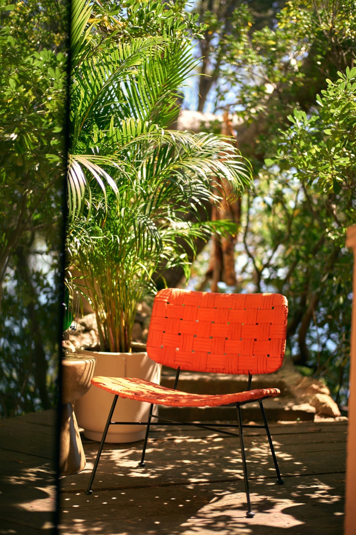 orange rattan lounge chair by HKLIVING styled on a sunlit patio with plants

