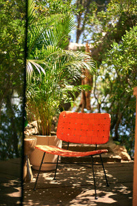 orange rattan lounge chair by HKLIVING styled on a sunlit patio with plants

