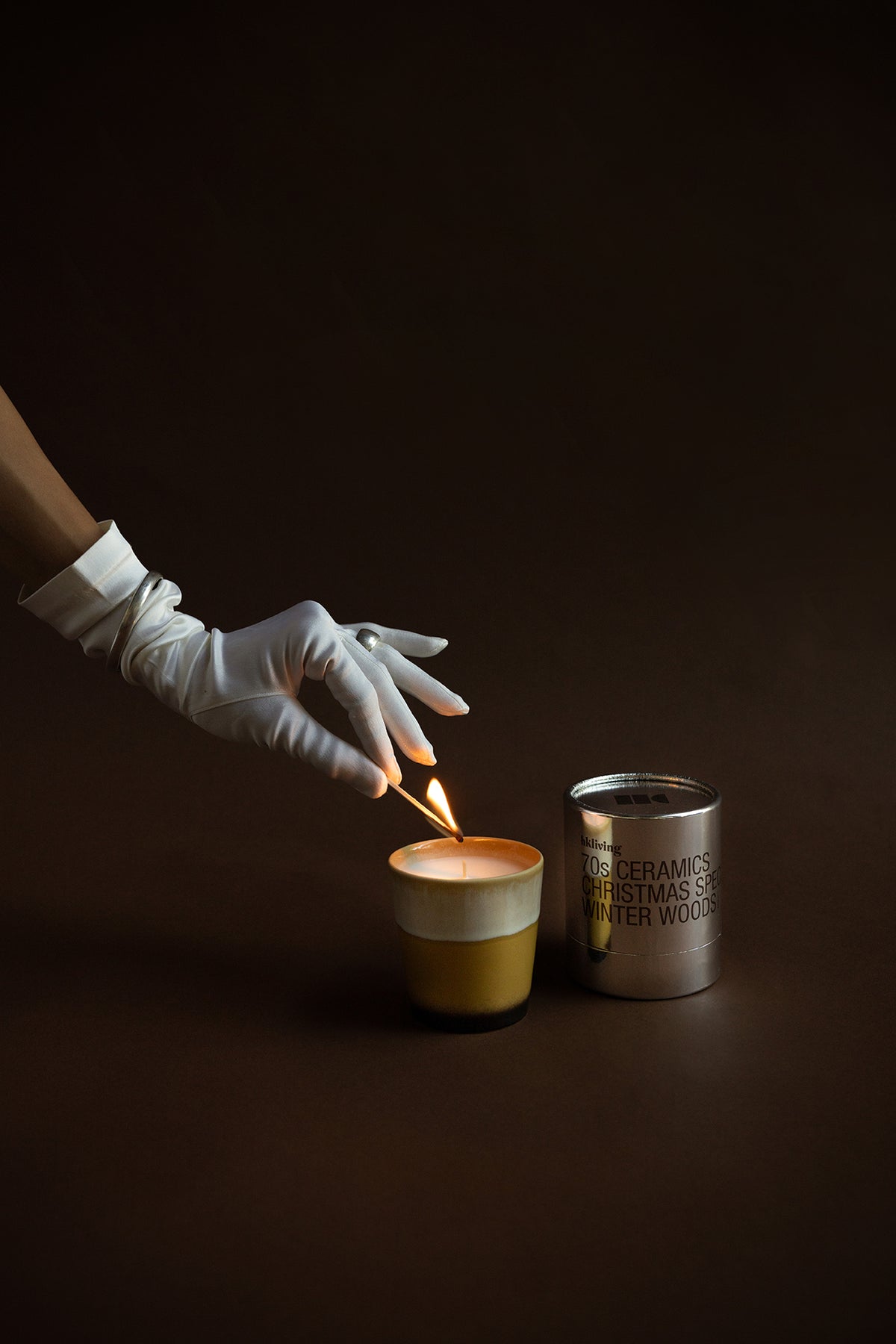 HKLIVING Winter Woods candle being lit – festive scene with elegant gloved hand
