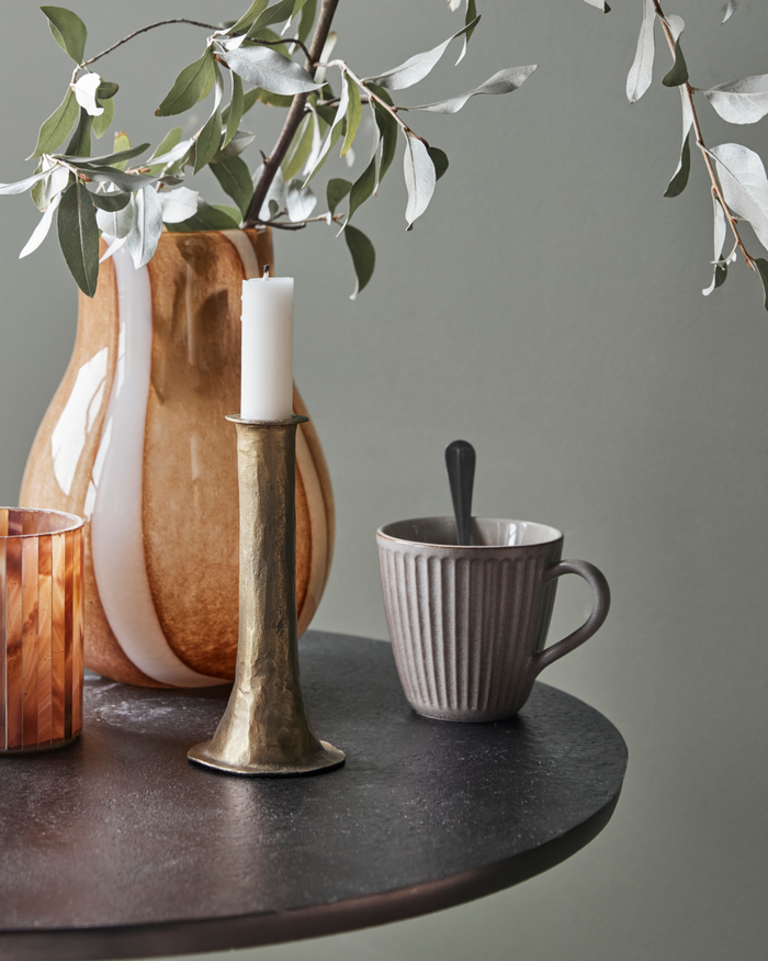 antique gold candle holder styled on table with mug, vase and candle for cosy home atmosphere