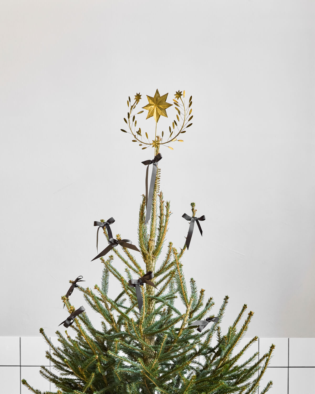 House Doctor Clip gold star topper on a Christmas tree decorated with black bows