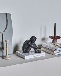 House Doctor Forms black seated figure sculpture on a pile of books beside stoneware vases