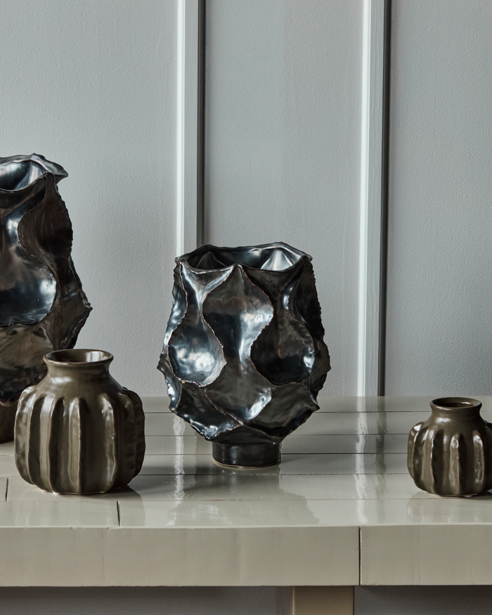 HDWaves antique metallic vase styled on a console with other ceramics in a modern interior.
