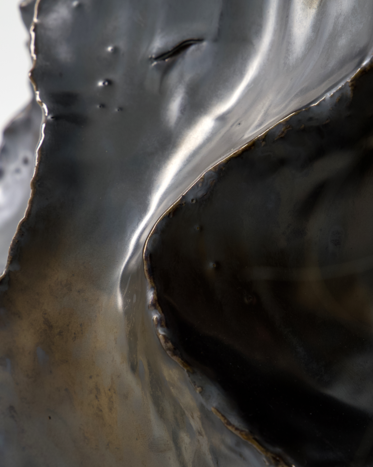 Sculptural edges of the HDWaves vase with layered metallic glaze highlights.
