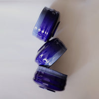 Three stacked indigo ceramic matcha bowls showing glaze variation and grooved sides