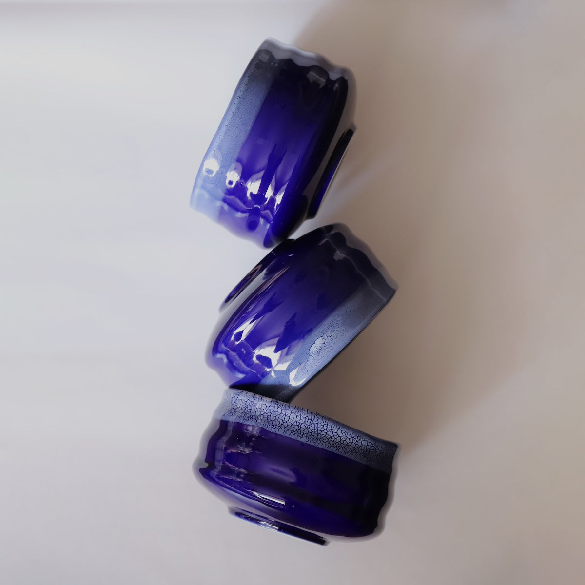 Three stacked indigo ceramic matcha bowls showing glaze variation and grooved sides