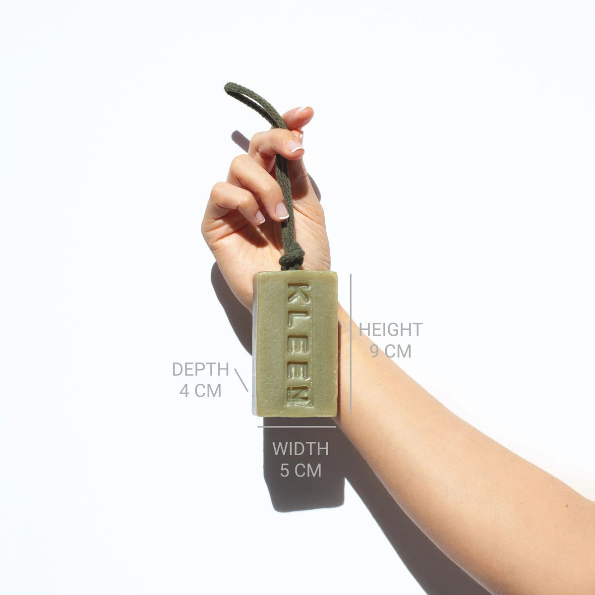 Hand holding the KLEEN Morning Glory soap bar with dimensions marked to show its size