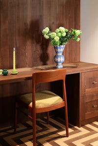 &klevering spiral taper candle styled with blue harlequin vase on warm wood desk
