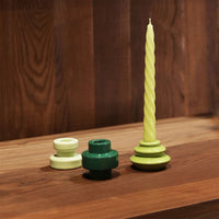 &k green spiral taper candle styled with glossy mini holders on a walnut desk

