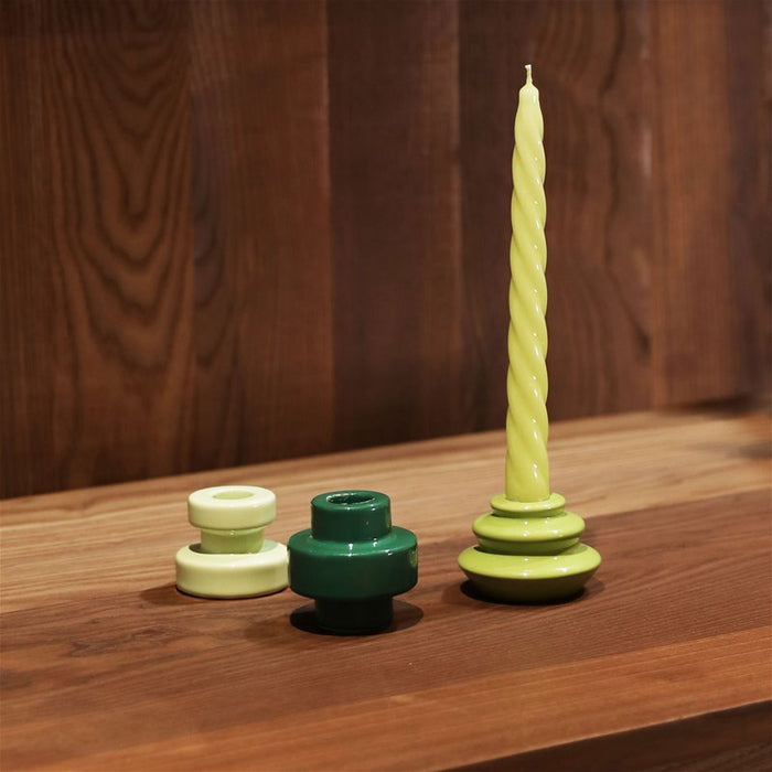 &k green spiral taper candle styled with glossy mini holders on a walnut desk
