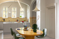 Bright kitchen with oval dining table and green chairs styled with &Klevering ceramics