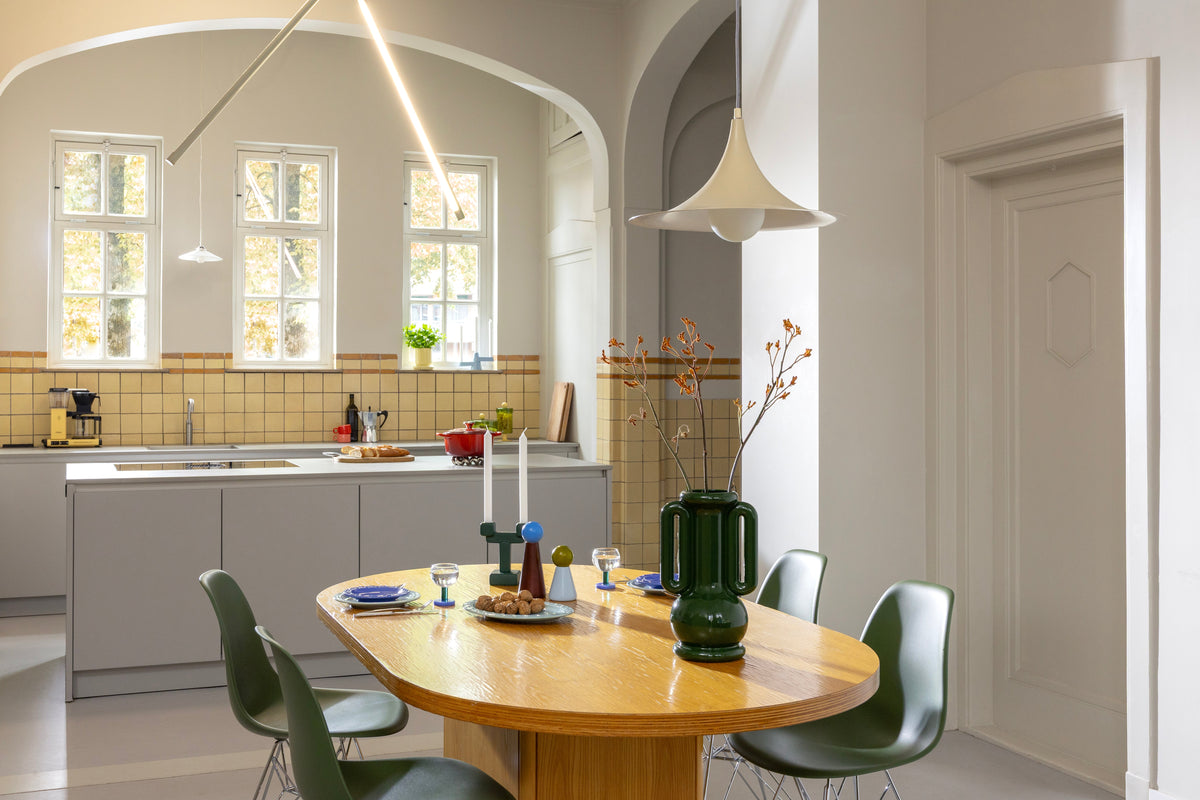 Bright kitchen with oval dining table and green chairs styled with &Klevering ceramics