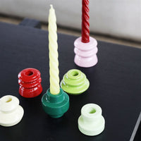 mix-and-match &klevering candle holders with pale yellow-green spiral taper on black table

