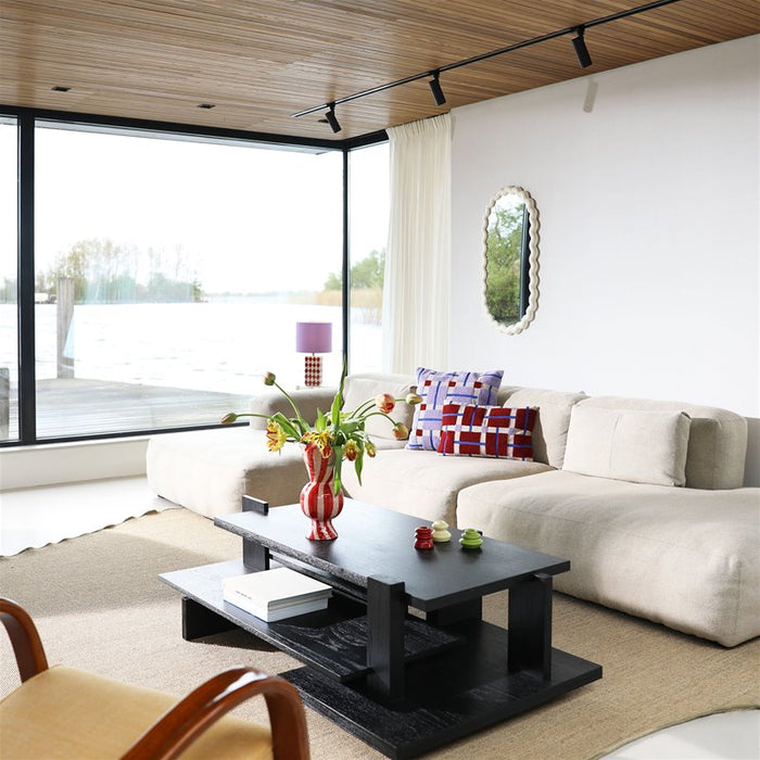red and white candy-stripe rhombic vase by &klevering on a black coffee table in a bright living room
